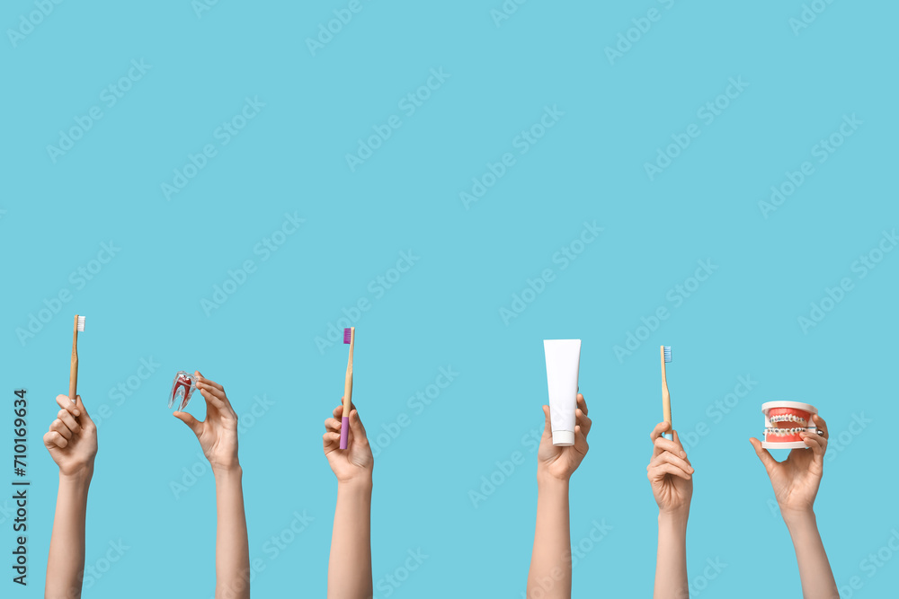 Female hands with dental models and oral hygiene supplies on blue background - obrazy, fototapety, plakaty 