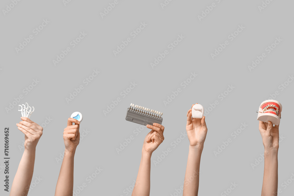 Female hands with dental floss, shade guide and jaw model on grey background - obrazy, fototapety, plakaty 