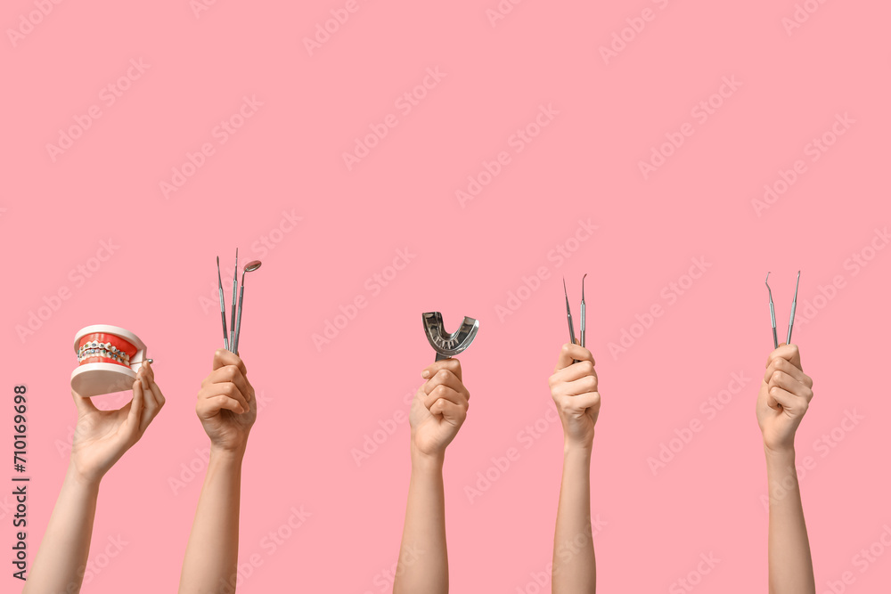 Female hands with dental tools and jaw model on pink background Female hands with dental tools and jaw model on pink background