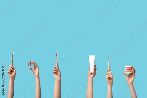 Female hands with dental models and oral hygiene supplies on blue background photo