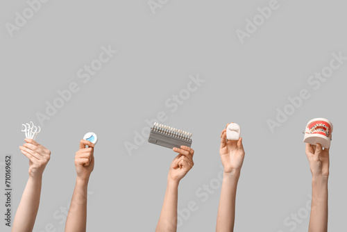 Female hands with dental floss, shade guide and jaw model on grey background
