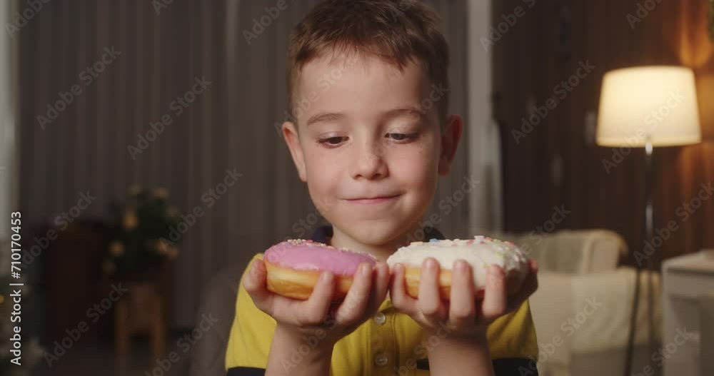 Caucasian child with an eating disorder quickly wants to eat two donuts at same time and cannot decide which donut to eat first. School boy eats two donuts at same time. Sweet addiction concept. 4K Caucasian child with an eating disorder quickly wants to eat two donuts at same time and cannot decide which donut to eat first. School boy eats two donuts at same time. Sweet addiction concept. 4K
