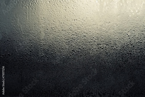 glass pane with condensation and water droplets, illuminated from one side creating a gradient effect.
