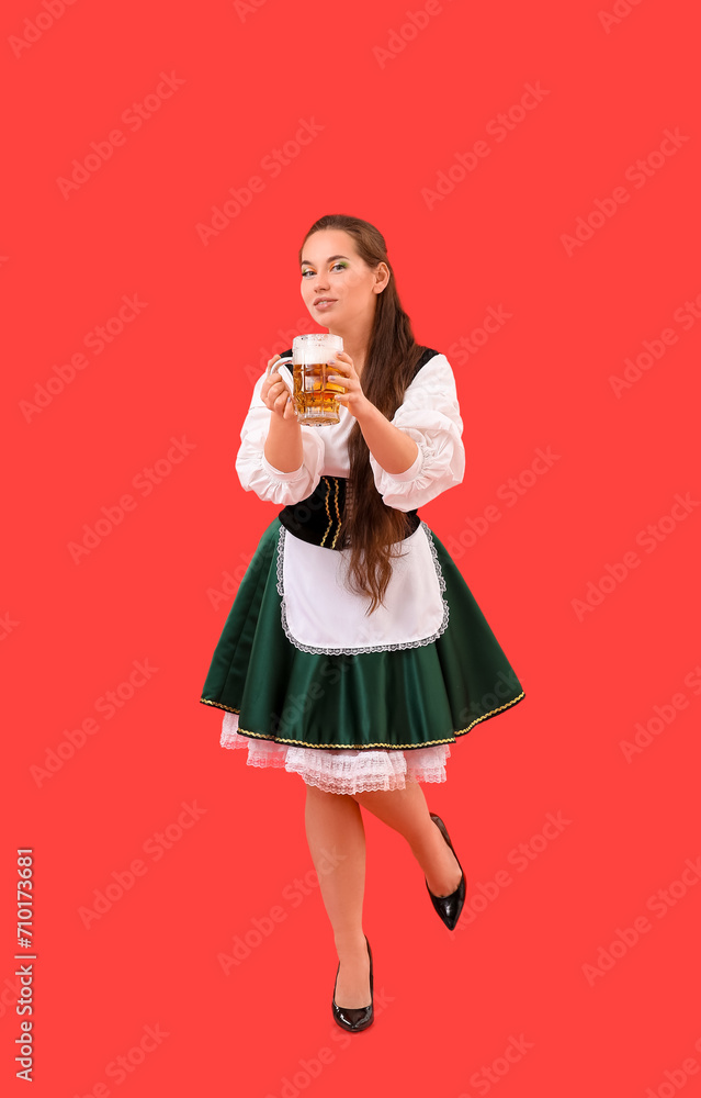 Young Irish woman with mug of beer on red background. St. Patrick's Day celebration