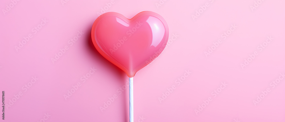 A heart-shaped lollipop against a pink backdrop on the day of love and friendship.
