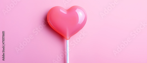 A heart-shaped lollipop against a pink backdrop on the day of love and friendship.