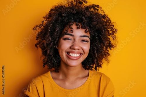 Cheerful girl with curly hair smiling on yellow background. © Vibu design  gallery