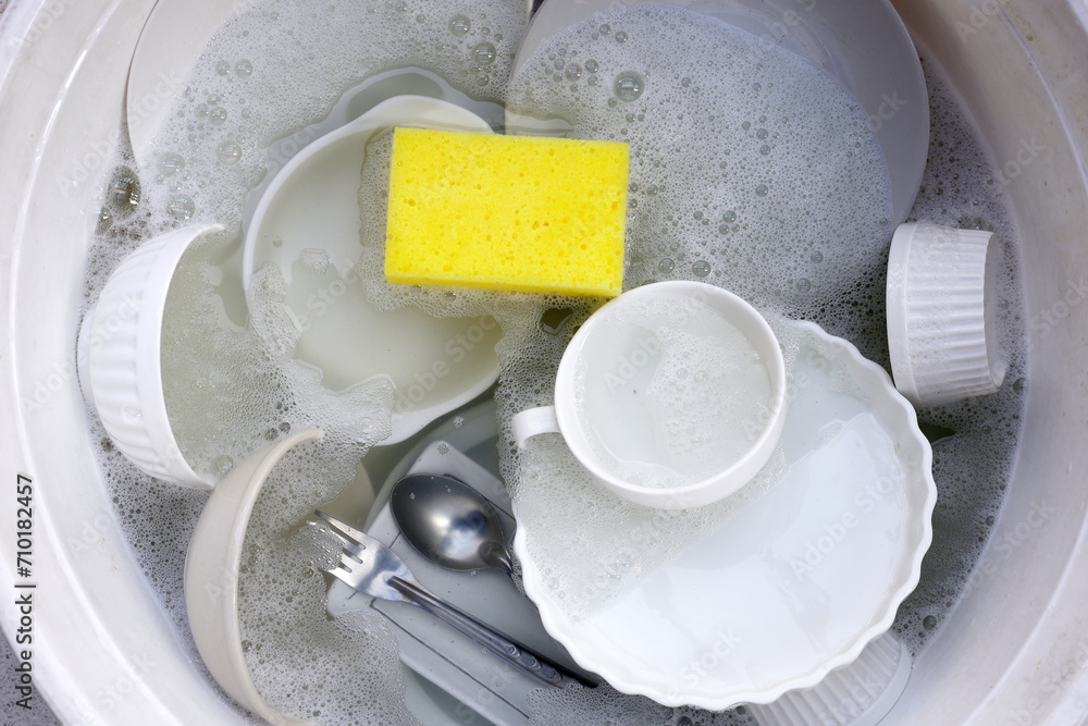 Dirty dishes with cleaning sponge in foam of dishwashing liquid. Washing dishes concept Dirty dishes with cleaning sponge in foam of dishwashing liquid. Washing dishes concept
