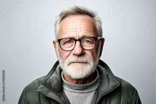 Portrait of an old man with grey beard and glasses on grey background © Iigo