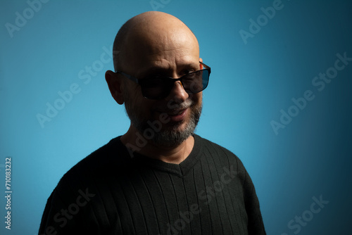 Portrait of bald and bearded mature man wearing sunglasses looking towards the camera.