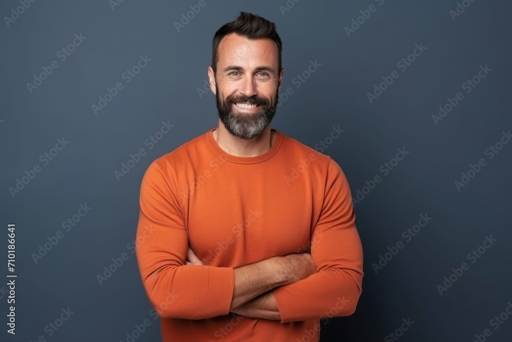 Portrait of a handsome man in an orange sweater with arms folded