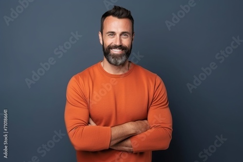 Portrait of a handsome man in an orange sweater with arms folded
