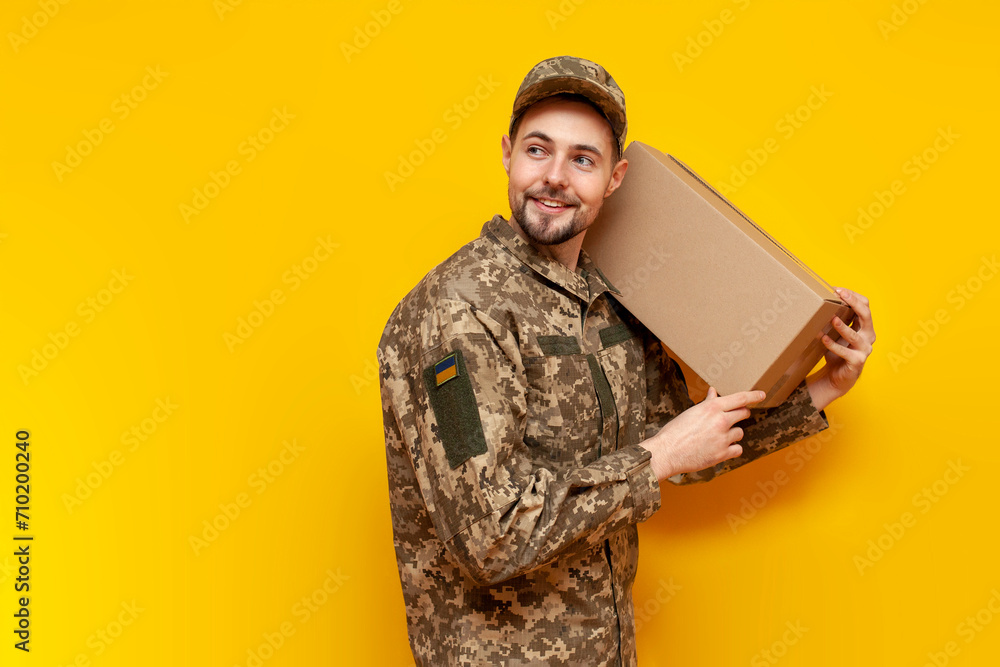 young Ukrainian male soldier in camouflage pixel uniform holding a box