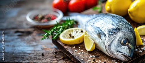 Selective focus on wooden background with raw dorada fish and ingredients. photo