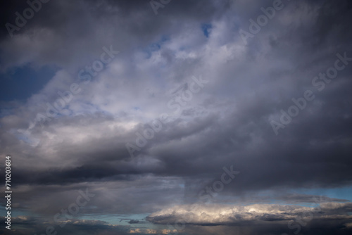 Epic Dramatic storm dark grey cumulus rain clouds against blue sky background texture, thunderstorm