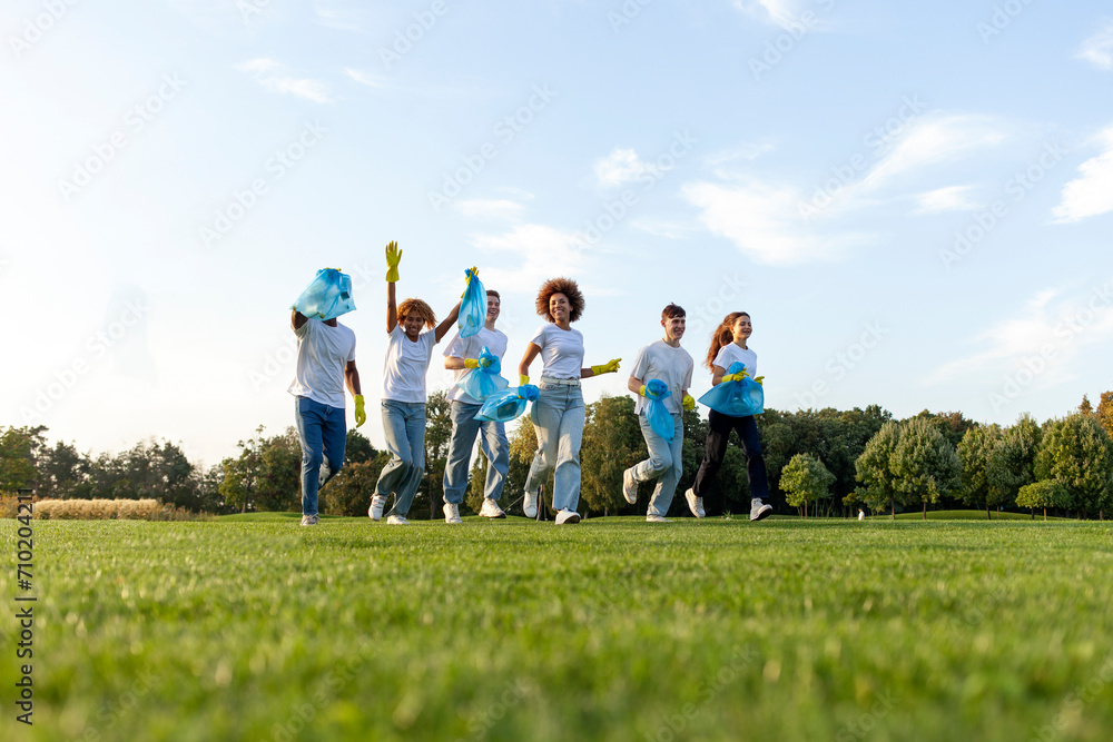 multiracial group of people running to clean the park from garbage and plastic with gloves and garbage bags, team of volunteers rejoice and celebrate outdoors, environmental care concept multiracial group of people running to clean the park from garbage and plastic with gloves and garbage bags, team of volunteers rejoice and celebrate outdoors, environmental care concept