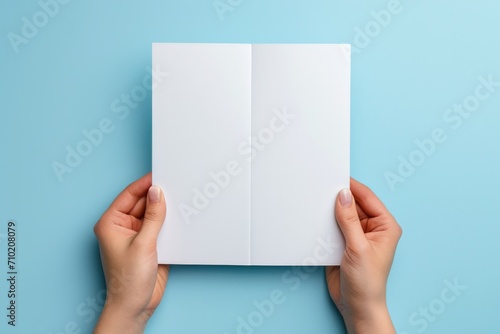 Mockup booklet presentation: Woman's hands hold blank white flyer on blue background photo