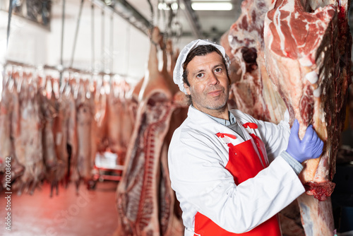 Male butcher showing beef chunk in meat storage