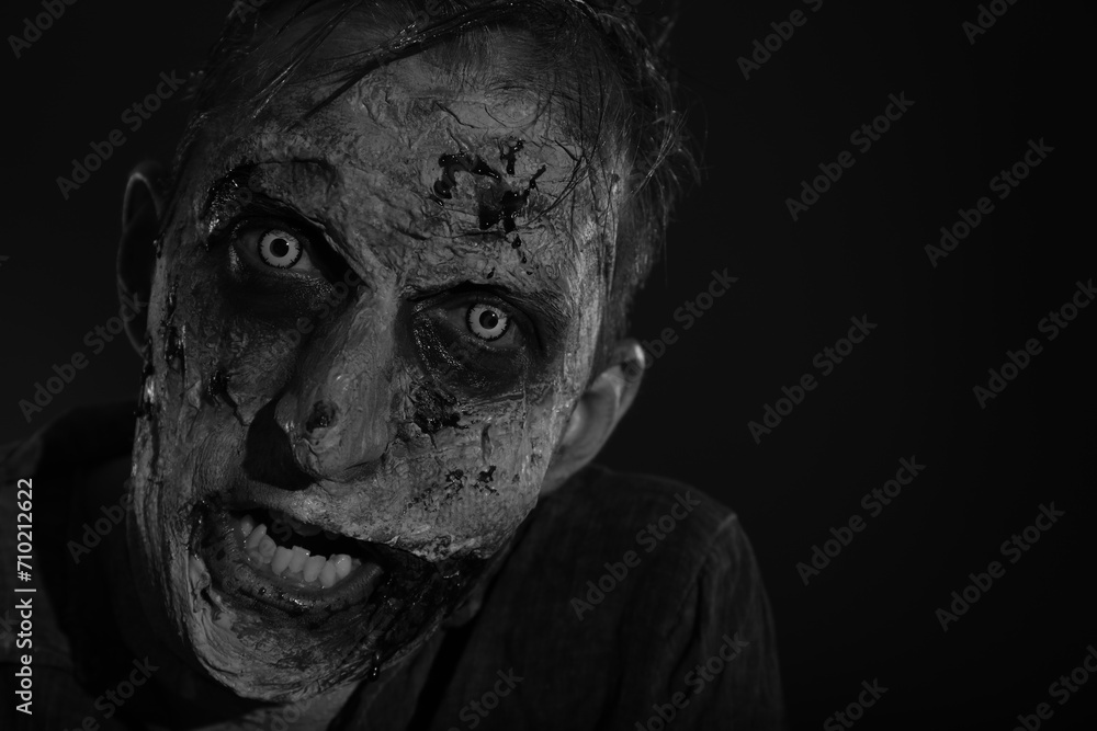 Scary zombie on dark background, black and white effect. Halloween monster