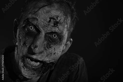 Scary zombie on dark background, black and white effect. Halloween monster