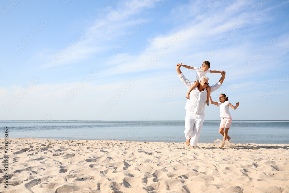 © New Africa - Cute little children with grandfather spending time together on sea beach