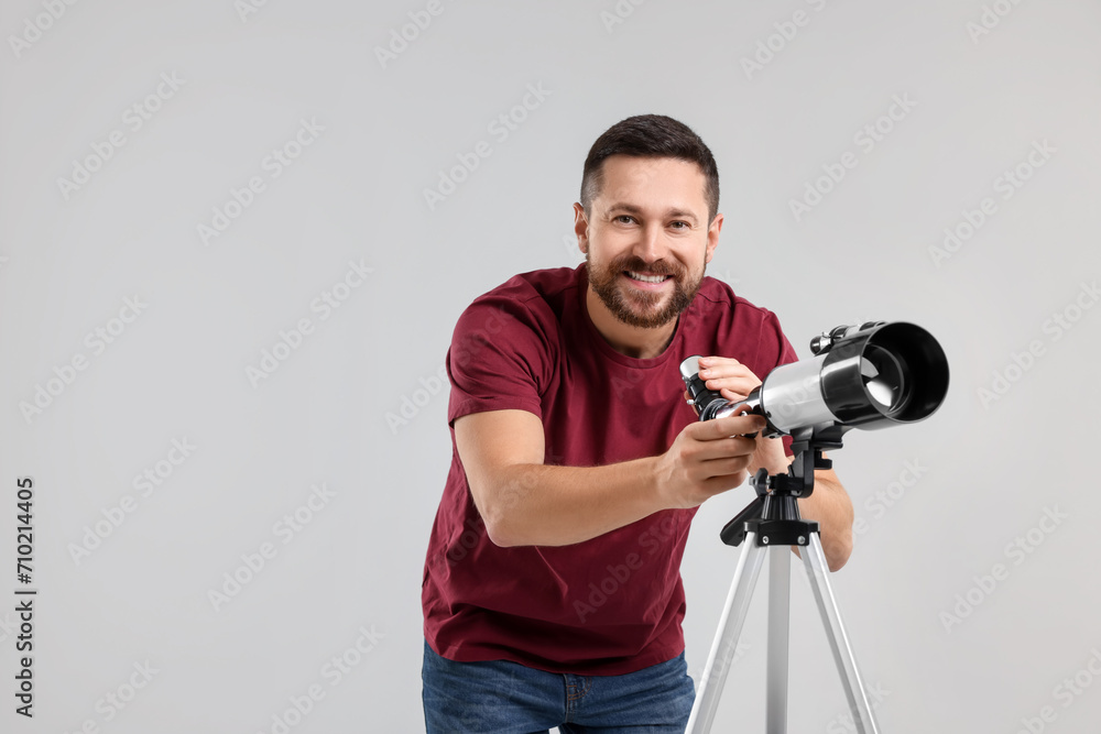 Obraz premium Smiling astronomer with telescope on light grey background. Space for text