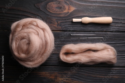 Beige felting wool and needles on wooden table, flat lay