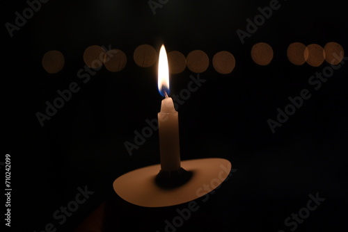 man holding white candle in the dark while it is lit