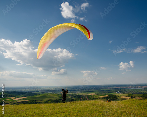 Man running high speed on field in nature ready to takeoff with paraglider 