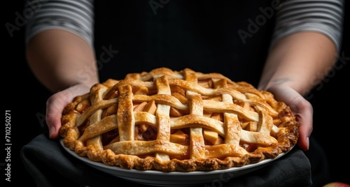 Closeup of woman holding plate with apple pie on black background