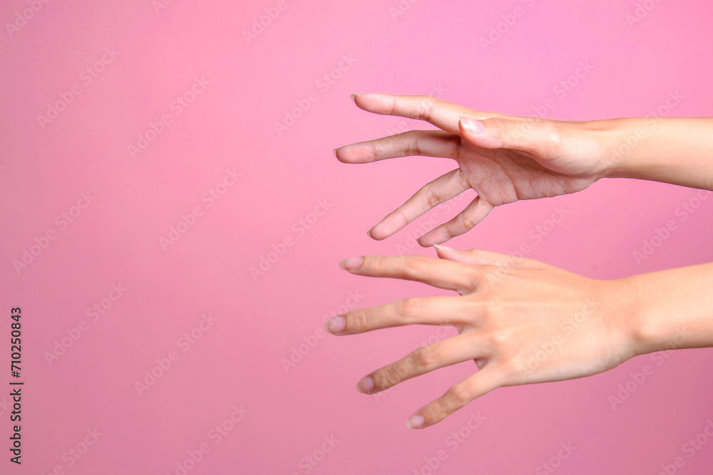Two female's hands trying to grab or reach something isolated over pink background - obrazy, fototapety, plakaty 