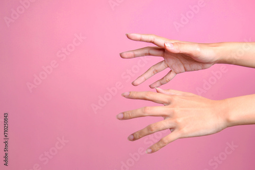 Two female's hands trying to grab or reach something isolated over pink background photo