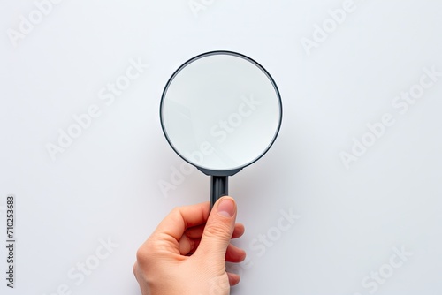 Hand holding magnifying glass over target board for business objectives on white background
