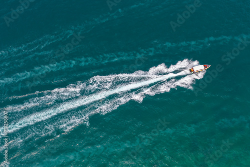 High speed boat rushing along the water surface of warm tropical waters, transfer of tourists. Aerial top view above © aapsky