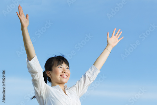 Happy Asian woman with arms raised upwards