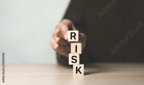 Risk management concept. Businessman hand put risk word on wooden block cube for financial banking analysis and business management. money risk assessment, Reducing project risk, finance, insurance,