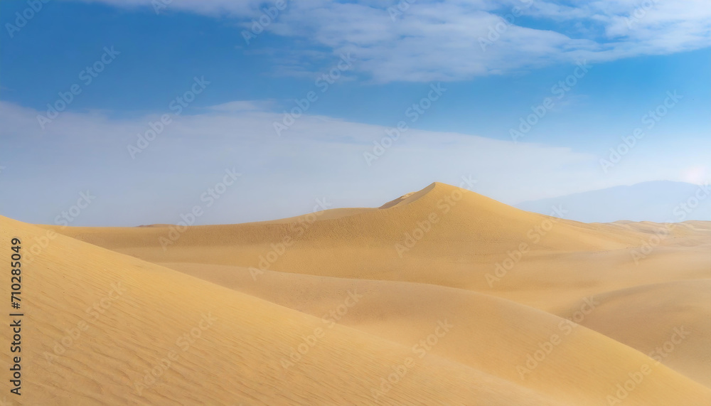   The image depicts a serene desert landscape with rolling sand dunes. The dunes are illuminated by the soft light of the setting sun, casting long shadows across the sand.