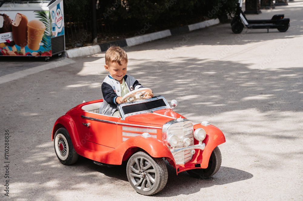 A little boy poses in a mini racing car. Play and relax in the fresh air. A little boy poses in a mini racing car. Play and relax in the fresh air.