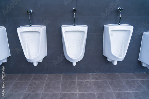 A row of urinals in tiled wall in a public restroom photo