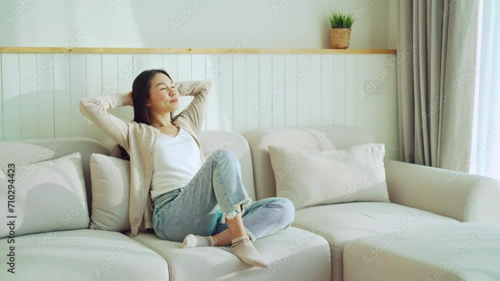 Carefree Asian woman relaxing and sitting on a sofa at home in the morning Carefree Asian woman relaxing and sitting on a sofa at home in the morning