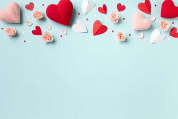 Saint Valentine day or Mother day background decorated with pink red hearts and roses flowers on blue table top view. Flat lay festive greeting card..