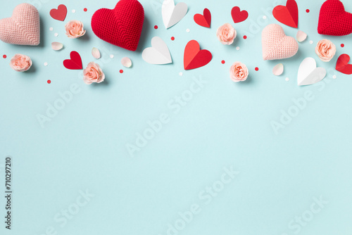 Saint Valentine day or Mother day background decorated with pink red hearts and roses flowers on blue table top view. Flat lay festive greeting card.. photo