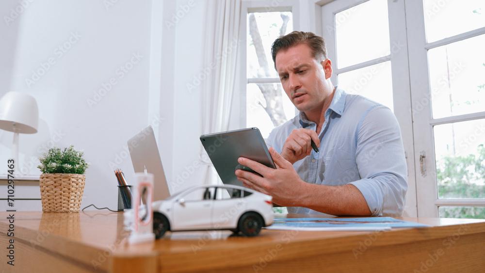 Stressed and frustrated car design engineer put his head in his hand after discover flaw in vehicle design, working at home for automotive business while trying to find solution. Synchronos