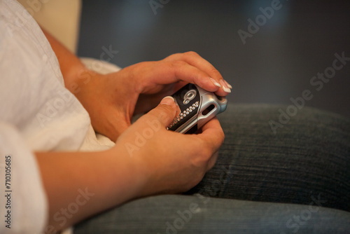 This image portrays a close-up of a person's hands holding an older model of a mobile phone, possibly from the early 2000s, suggesting a moment of connection or communication. The person is seated