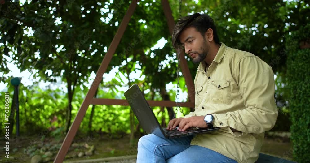 Nepali Bungo male sits in the park of Nepal, writes content on Laptop, studies in green environment drone shot, advertising 4K Nepali Bungo male sits in the park of Nepal, writes content on Laptop, studies in green environment drone shot, advertising 4K