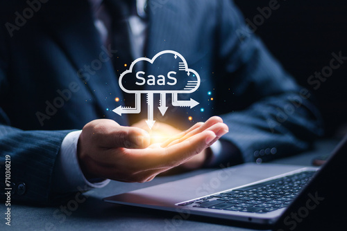 SaaS (software as a service) concept, Businessman use laptop with virtual screen of SaaS icons for software services on cloud system. Internet and networking technology.