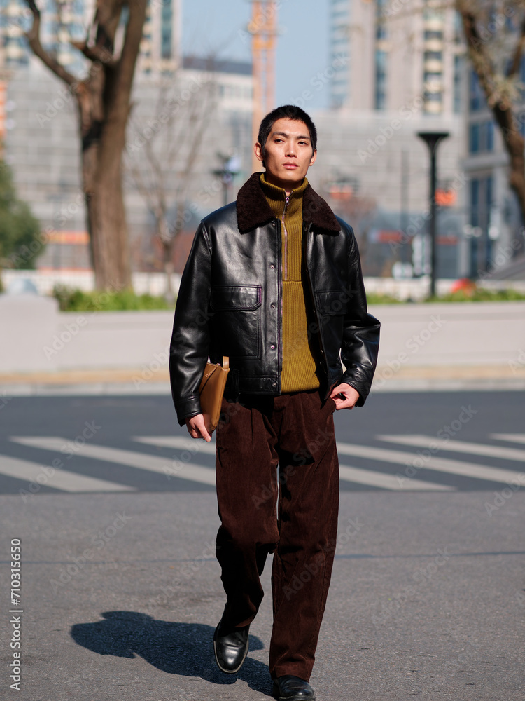 Portrait of handsome Chinese young man with black leather jacket posing with modern city street background in sunny winter day, male fashion, cool Asian young man. Portrait of handsome Chinese young man with black leather jacket posing with modern city street background in sunny winter day, male fashion, cool Asian young man.