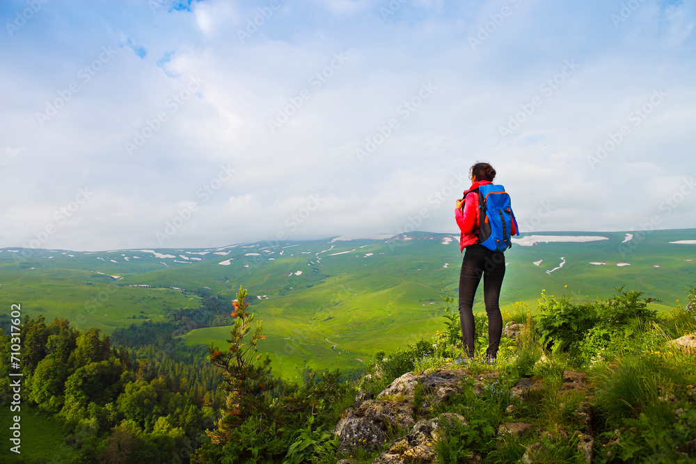 Hiker with backpack on top of mountain and enjoying valley view