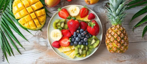 Tropical beach lifestyle with fresh fruit plate and pineapple, top view. photo