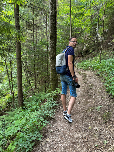 A man with a camera and a backpack walks in the forest